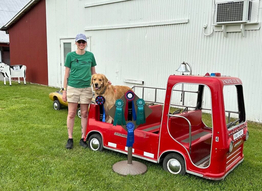 Dog and owner calmly standing for a picture with award ribbons